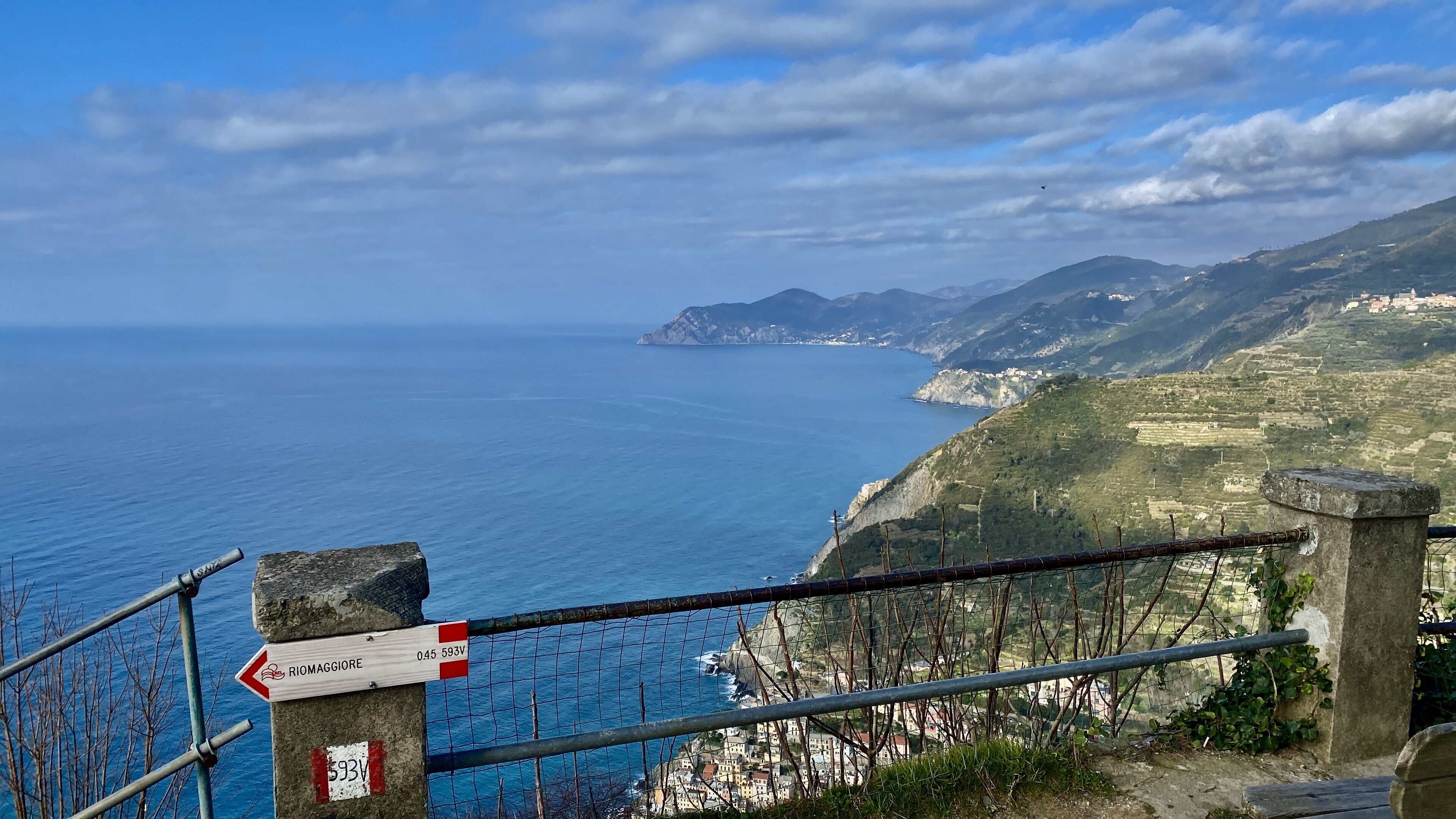 Vista costanera amb un senyal que indica 'Riomaggiore' i un marcadors de distància de 0,45 km.