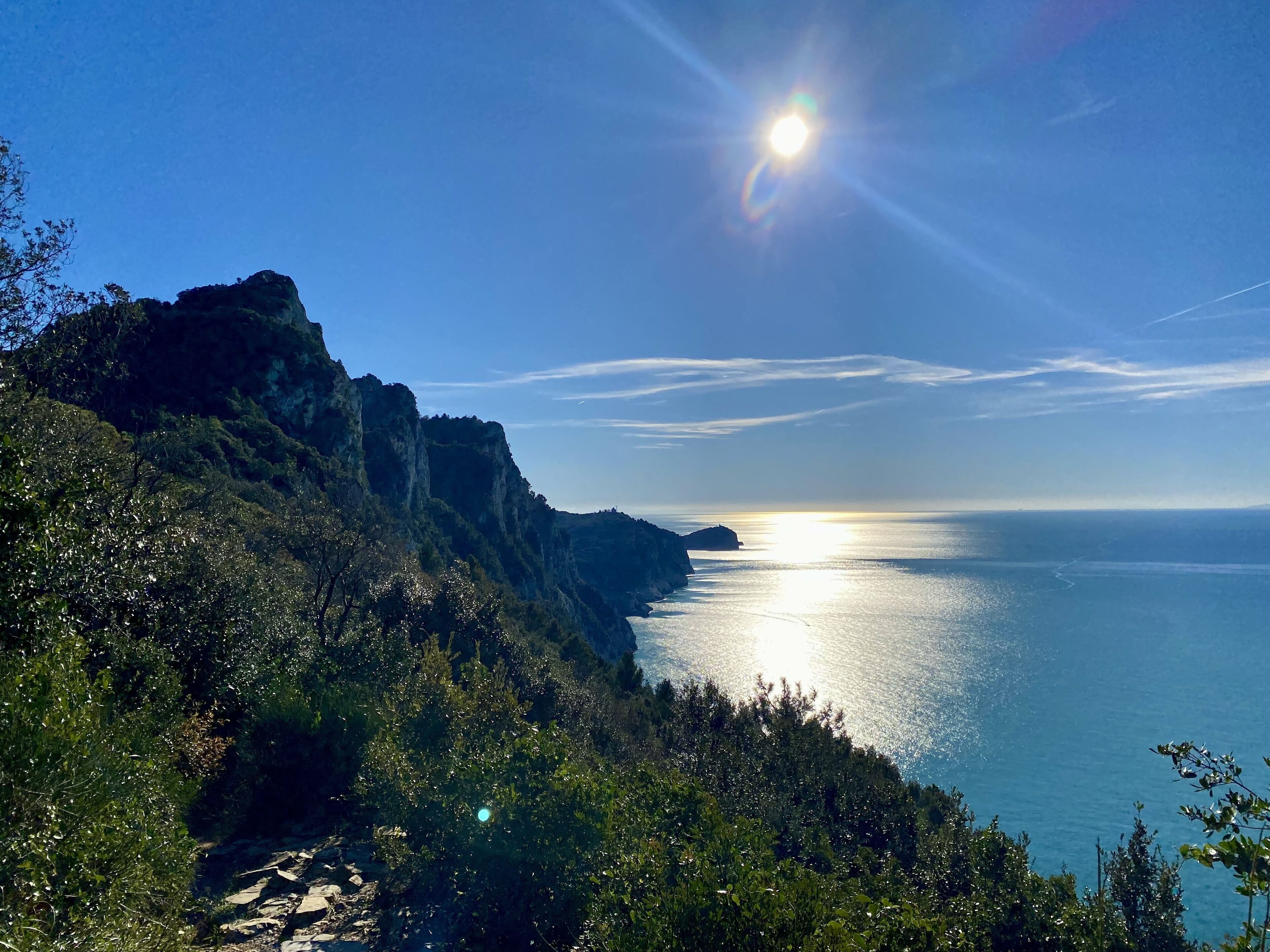 A coastal landscape with a clear sky, a rocky cliff, and a calm sea.