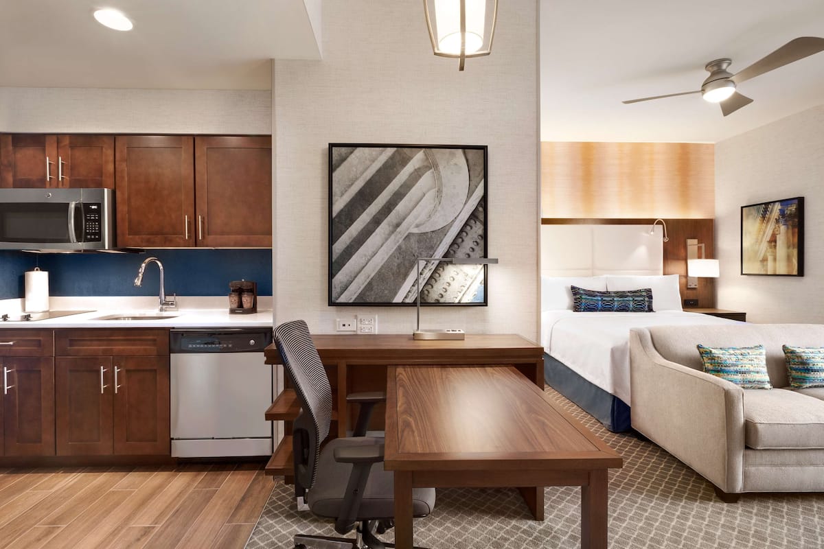 Une chambre d’hôtel moderne équipée d’une kitchenette, d’un coin repas, d’un canapé et d’un lit.