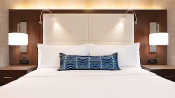 A hotel room with a large bed, two bedside tables, and a headboard with integrated lighting.