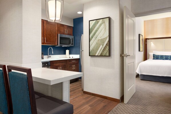 A hotel room with a bed, a small kitchenette, and a dining area. - Homewood Suites by Hilton Arlington Rosslyn Key Bridge (Arlington)