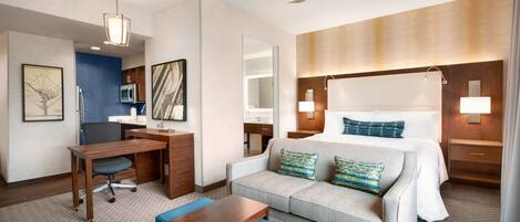 A hotel room with a bed, a desk, a chair, a sofa, and a small table.