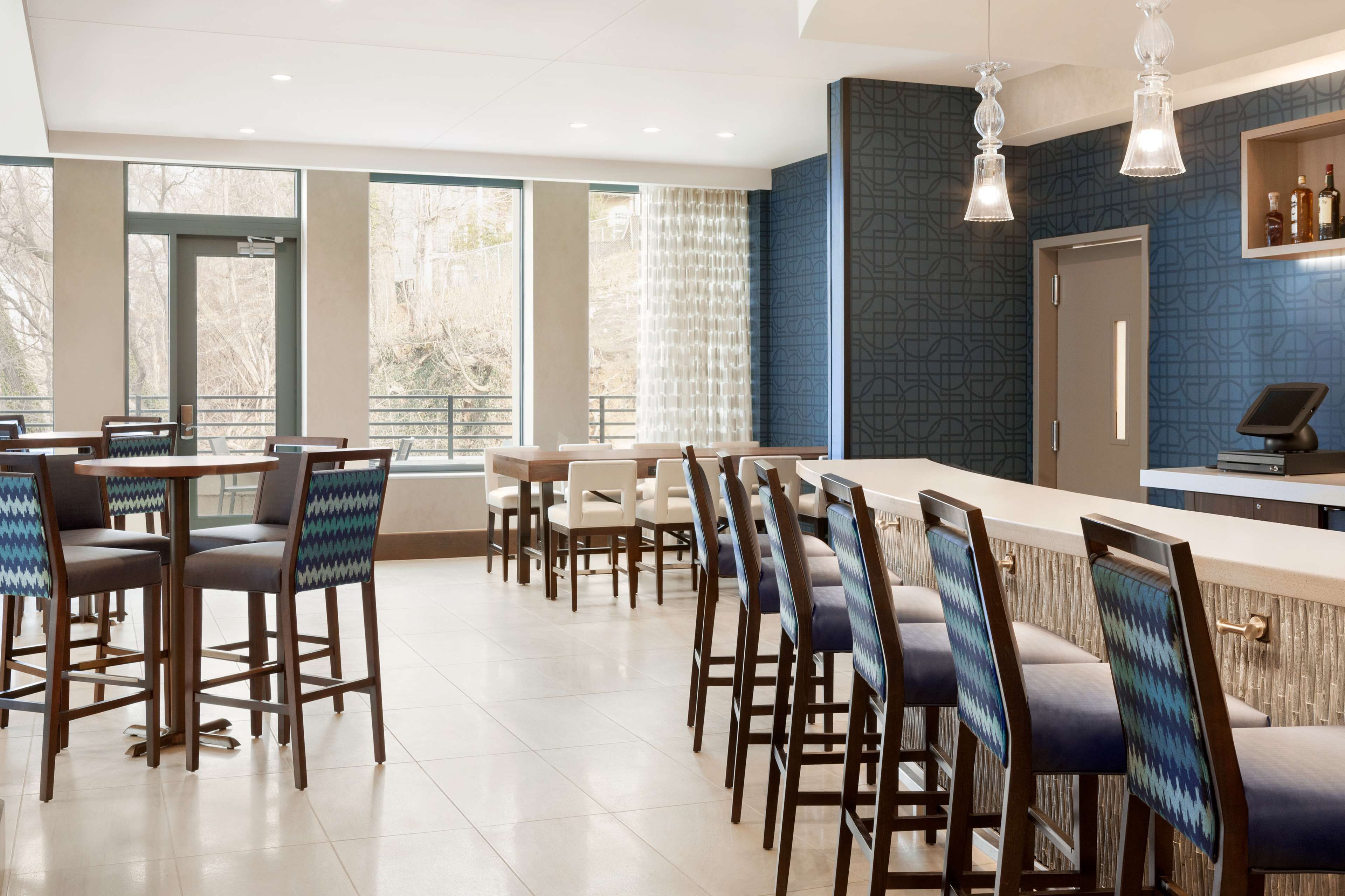A modern bar area with high stools, a counter, and pendant lighting.