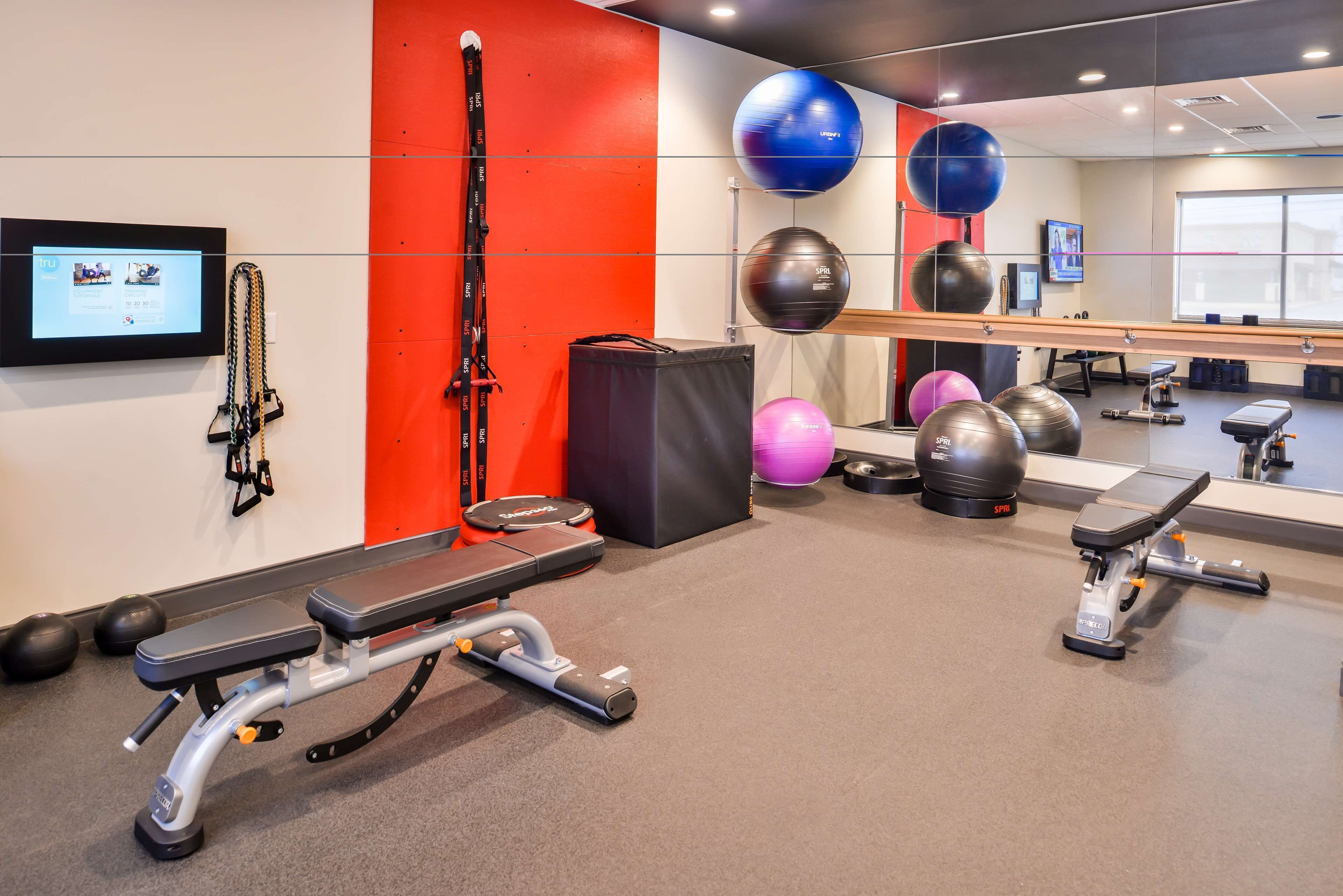A gym with exercise equipment, a wall-mounted TV, and a mirror.
