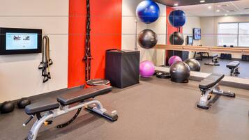 A gym with exercise equipment, a wall-mounted TV, and a mirror.