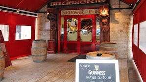 Entrada a un pub con un cartel que dice "PUB BRASSERIE" y una pizarra con la carta de Guinness.