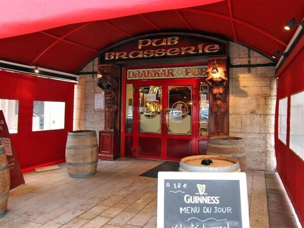A pub entrance with a sign reading "PUB BRASSERIE" and a Guinness menu board.