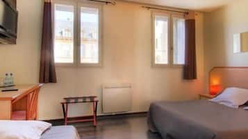 Habitación de hotel con dos camas, un escritorio, una silla y una ventana con cortinas.