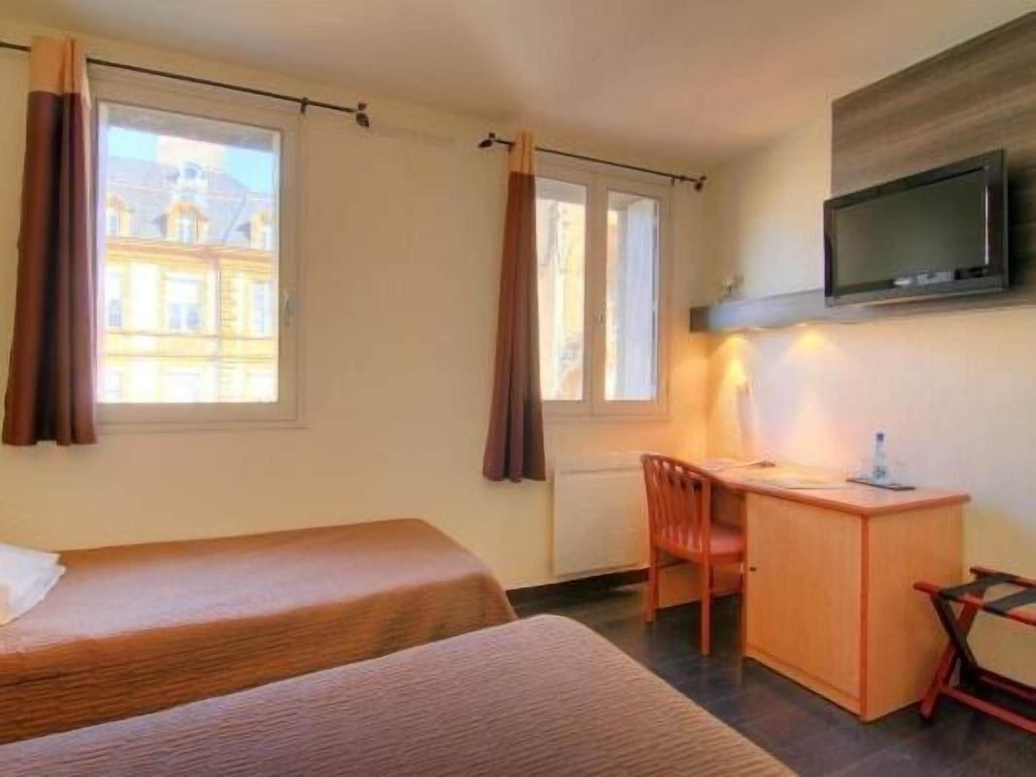 Een hotelkamer met twee bedden, een bureau, een stoel, een televisie en een raam met gordijnen.