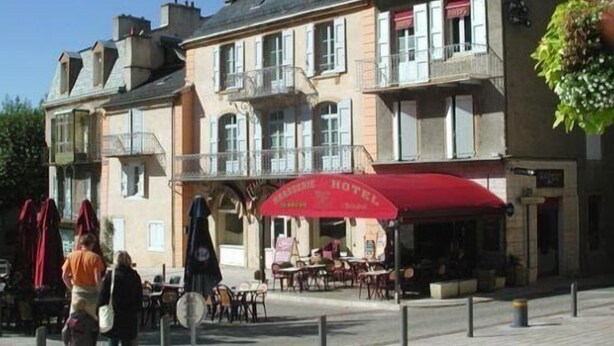 A hotel with outdoor seating and a red awning. - Hôtel Le Drakkar (Mende)