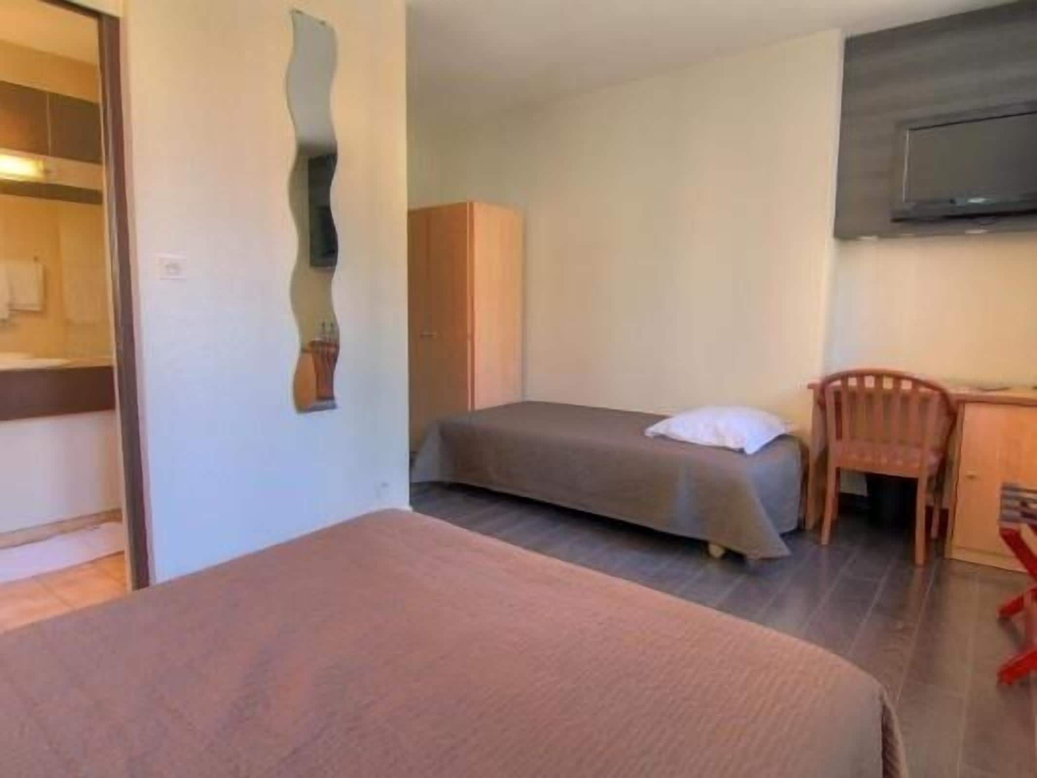 Un dormitorio con cama, una silla, armario y televisor.