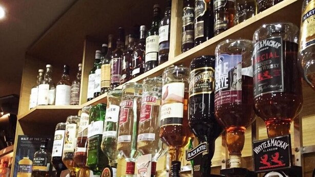 Un bar con scaffali pieni di bottiglie di alcolici e bicchieri.