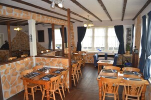 Un restaurante con paredes de piedra, mesas y sillas de madera, y un pilar de piedra.