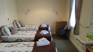 Camera d'albergo con due letti, una scrivania, una sedia, un comò e bagno con lavandino e specchio.
