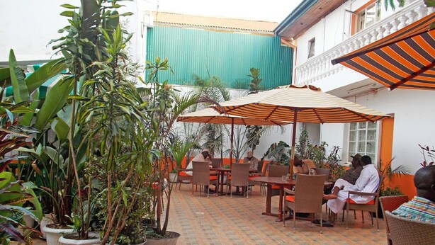 An outdoor patio area with potted plants, tables, and chairs. - Hanan Guest House (Nairobi)