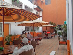 An outdoor dining area with tables and chairs, umbrellas, and potted plants. - Hanan Guest House (Nairobi)