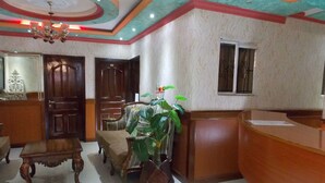 A reception area with a wooden desk, a reception counter, a chair, and a potted plant. - Hanan Guest House (Nairobi)