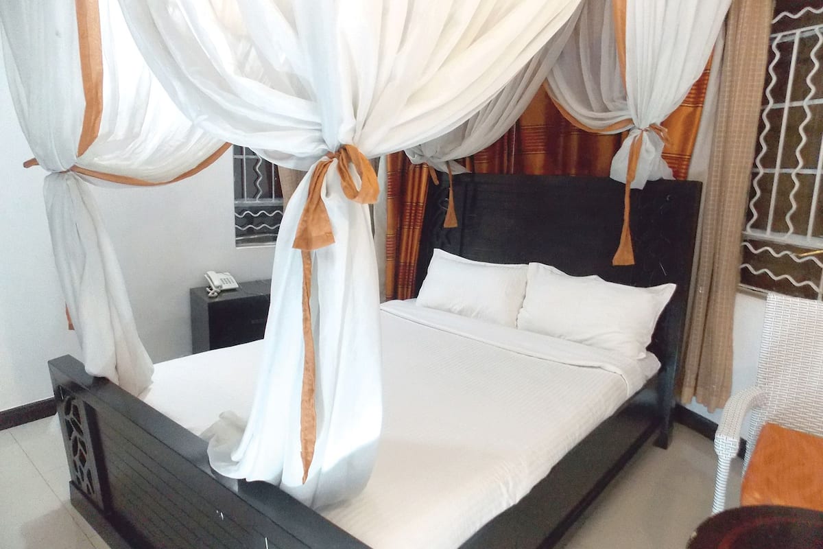 A bed with a canopy, a nightstand, and a chair.