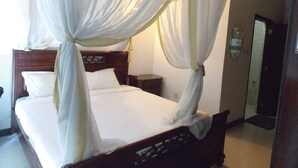 A bed with a canopy, a wooden headboard, and a nightstand with a lamp. - Hanan Guest House (Nairobi)