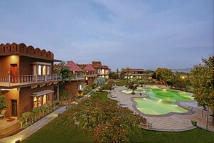 A resort with a pool, outdoor seating, and traditional architecture.