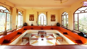 A room with a large, curved sofa set, a central coffee table, and a patterned floor.