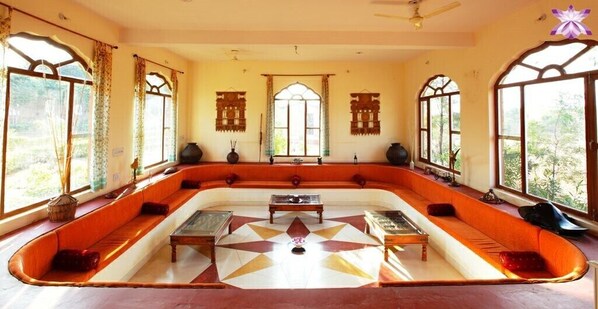 A room with a large, curved sofa set, a central coffee table, and a patterned floor. - Pushkar Fort - Luxury Heritage Resort  (Pushkar)