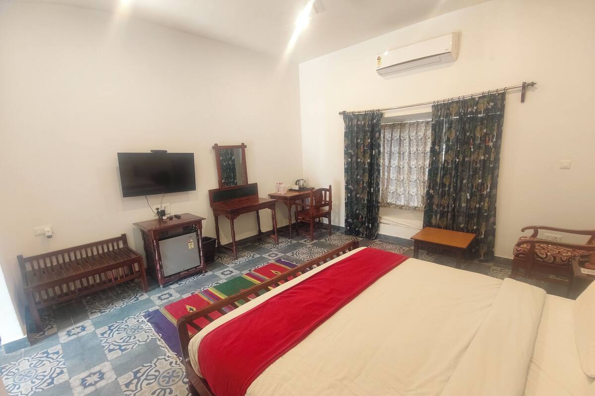 A hotel room with a bed, a desk, a chair, a television, and a window with curtains.