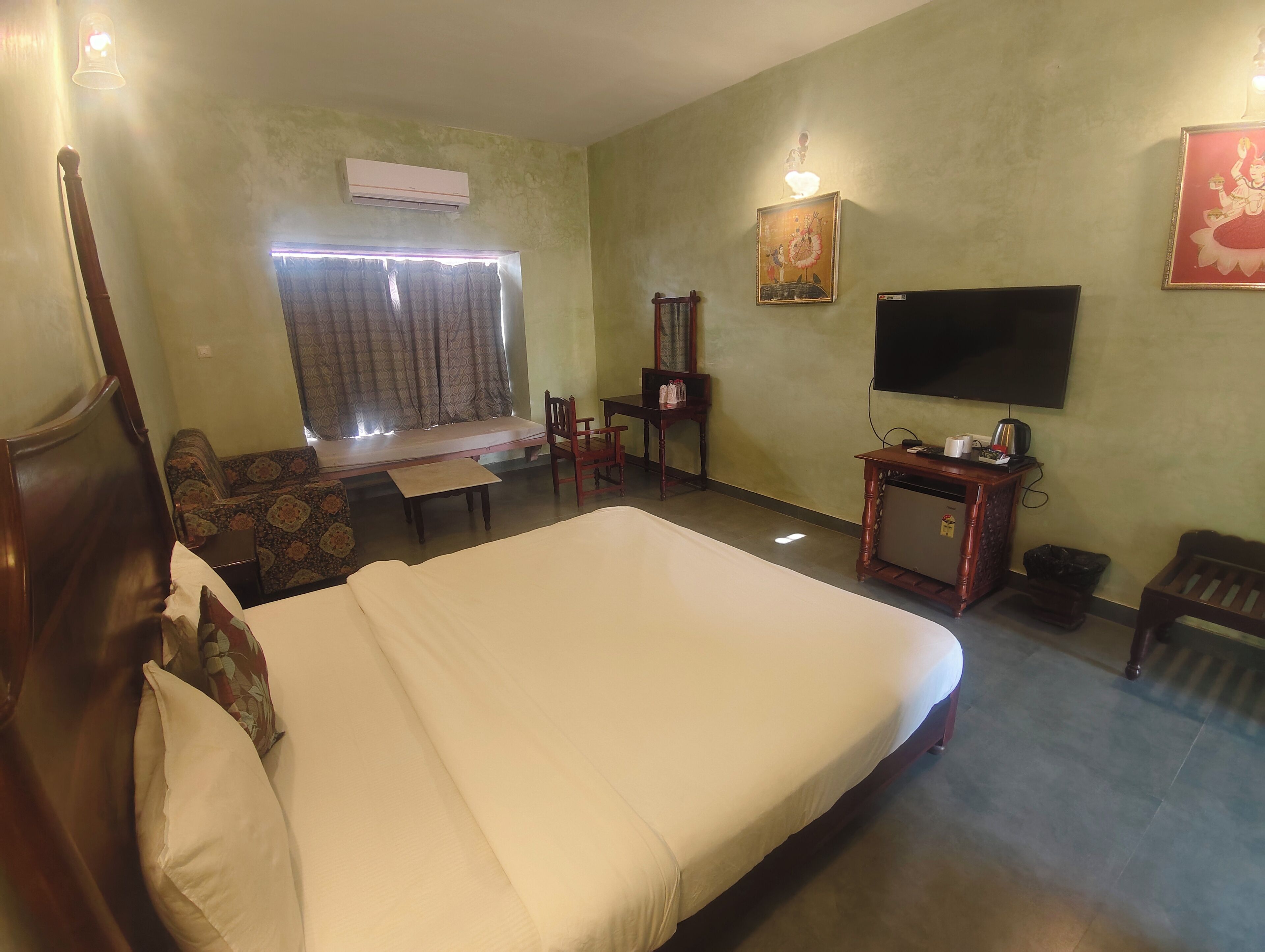 A hotel room with a bed, a desk, a chair, a television, and a window with curtains.