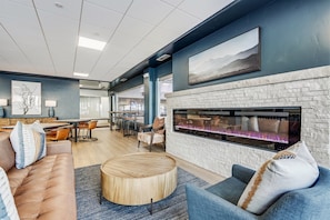 A modern lounge area with a stone fireplace, comfortable seating, and a view of the city through large windows. - Sky Mountain Studio (Breckenridge)