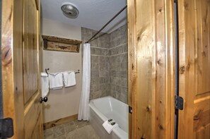 A bathroom with a bathtub, shower curtain, and tiled walls.