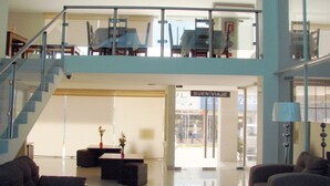 Eine geräumige Lobby mit hoher Decke, einer Treppe und einer Rezeption.