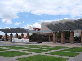 Una plaza con un gran letrero que dice 'Chihuahua', toldos solares y una escultura central.