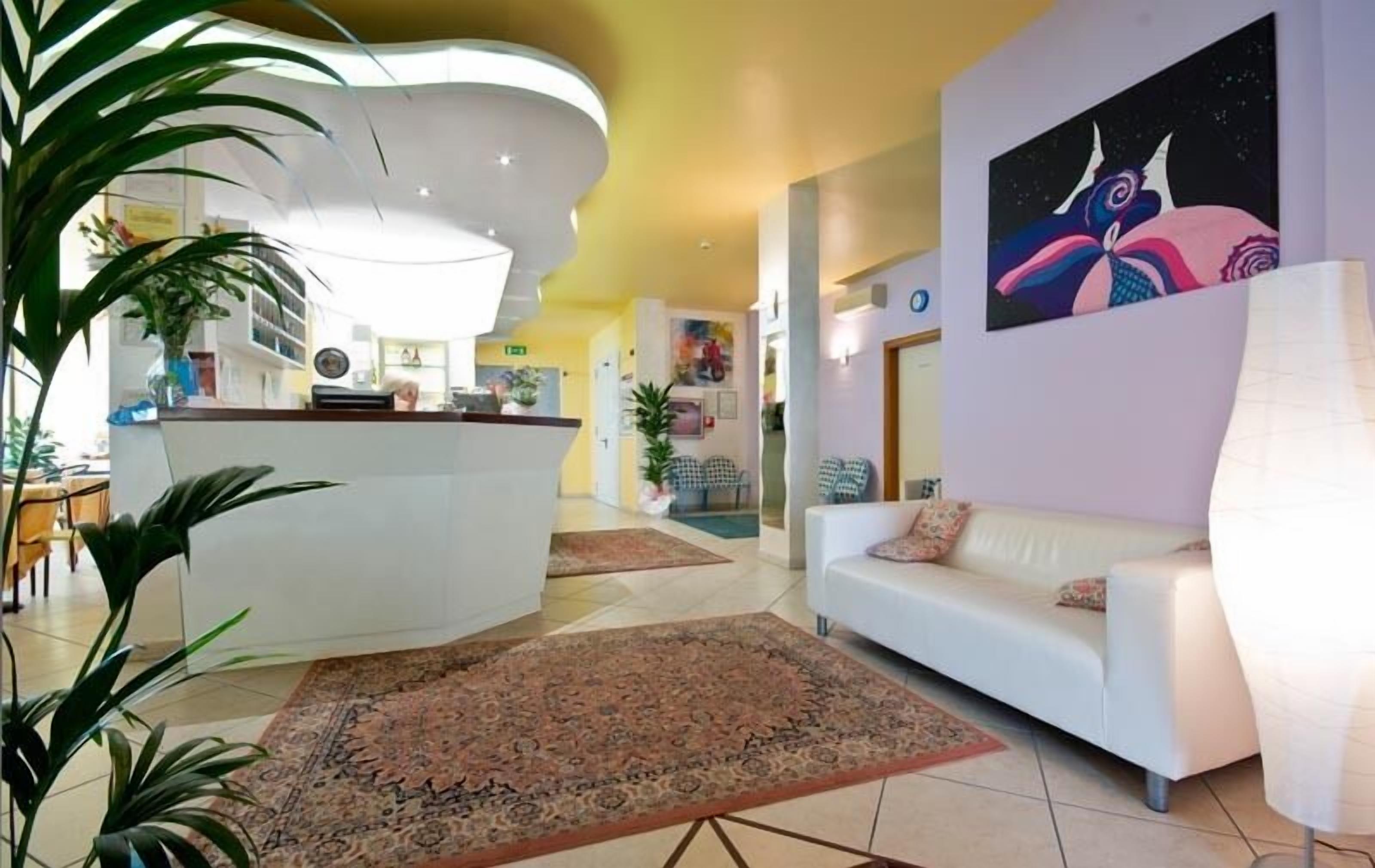 A modern lobby with a reception desk, a white sofa, and a large painting on the wall.