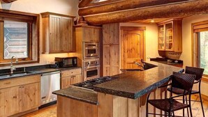 A spacious kitchen with wooden cabinets, a central island, and a large window. - Big Timber Lodge (Breckenridge)