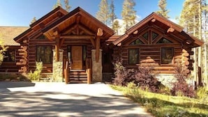 A log cabin with a central entrance, stone pillars, and a surrounding landscape. - Big Timber Lodge (Breckenridge)
