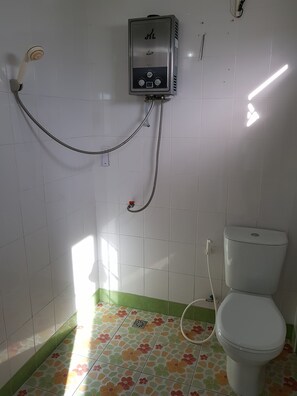 A bathroom with a shower, toilet, and a water heater mounted on the wall.