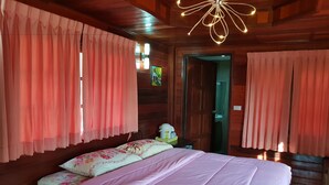 A wooden cabin bedroom with a bed, pink curtains, and a unique ceiling light fixture. - Norn Nee at Khaokho (Khao Kho)