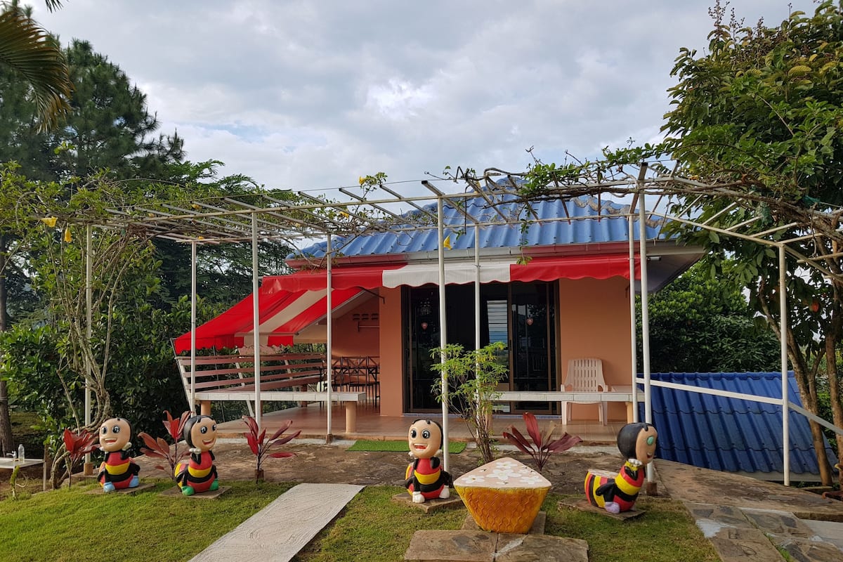 A covered patio area with a red and white awning, outdoor seating, and decorative bee statues.