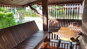 A wooden bench and table in a covered outdoor area with a view of greenery and buildings. - Norn Nee at Khaokho (Khao Kho)
