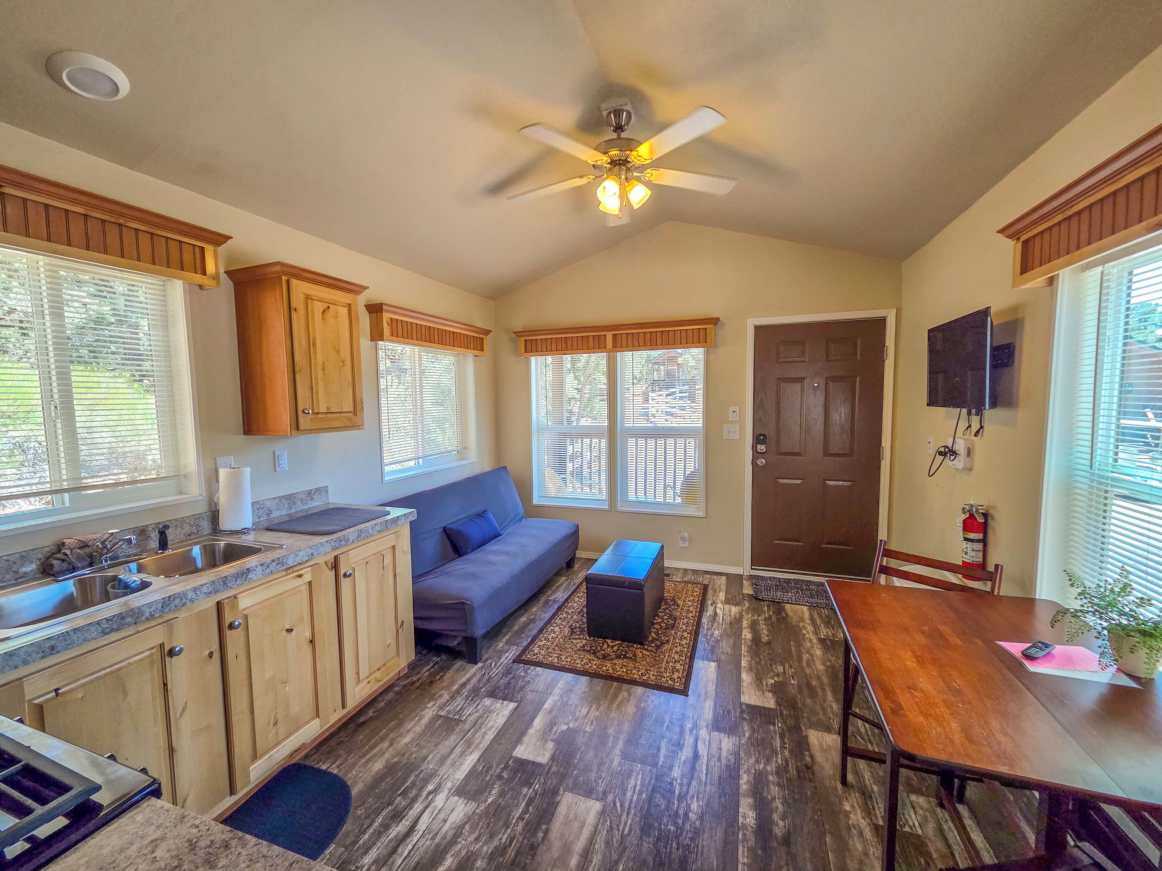 A compact kitchen with wooden cabinets, a built-in sink, and a ceiling fan.