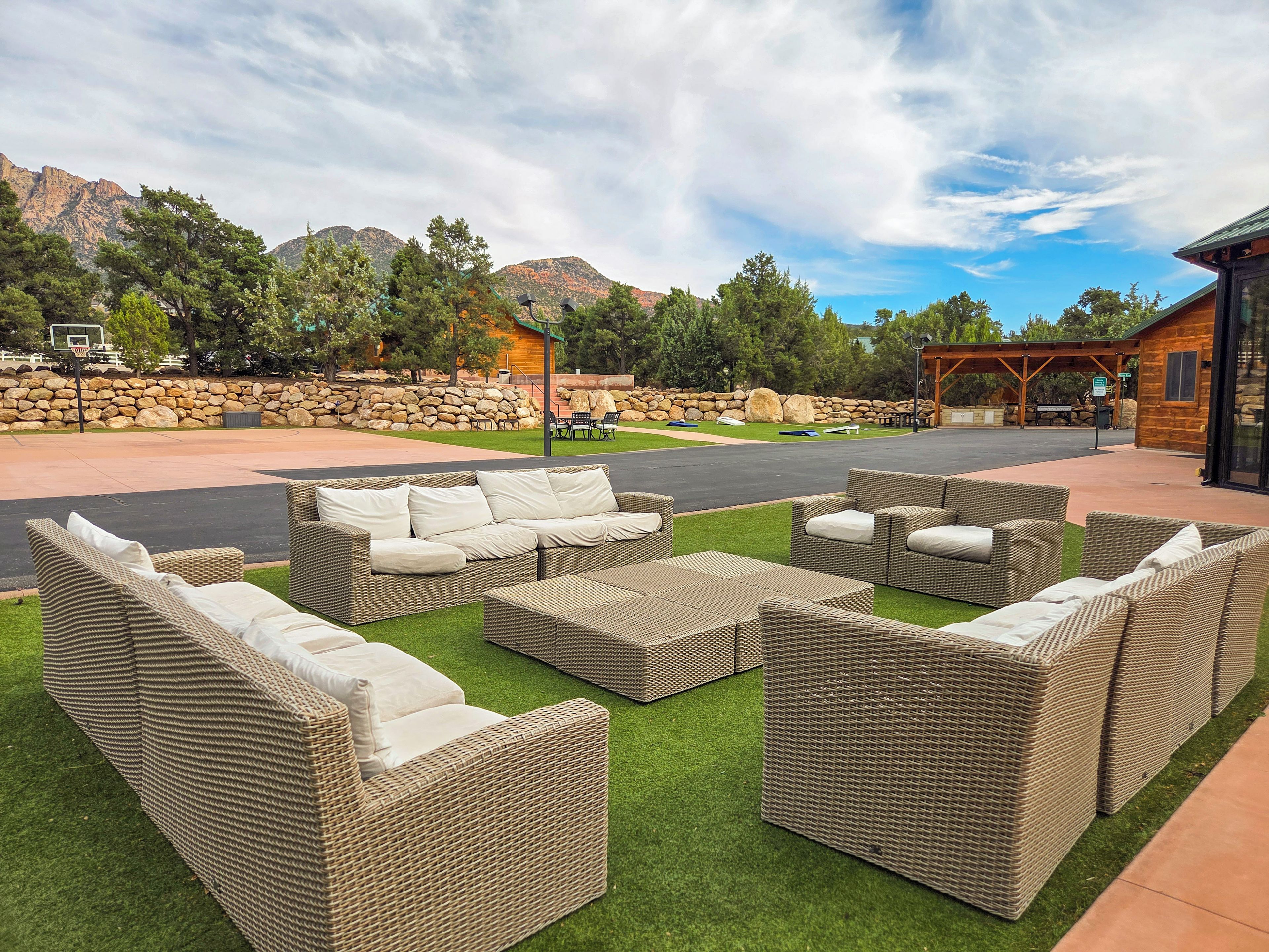 An outdoor seating area with wicker furniture and a stone wall backdrop.