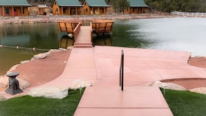 A wooden dock leading to a lake with cabins in the background. - Holmstead Ranch Resort (Veyo)