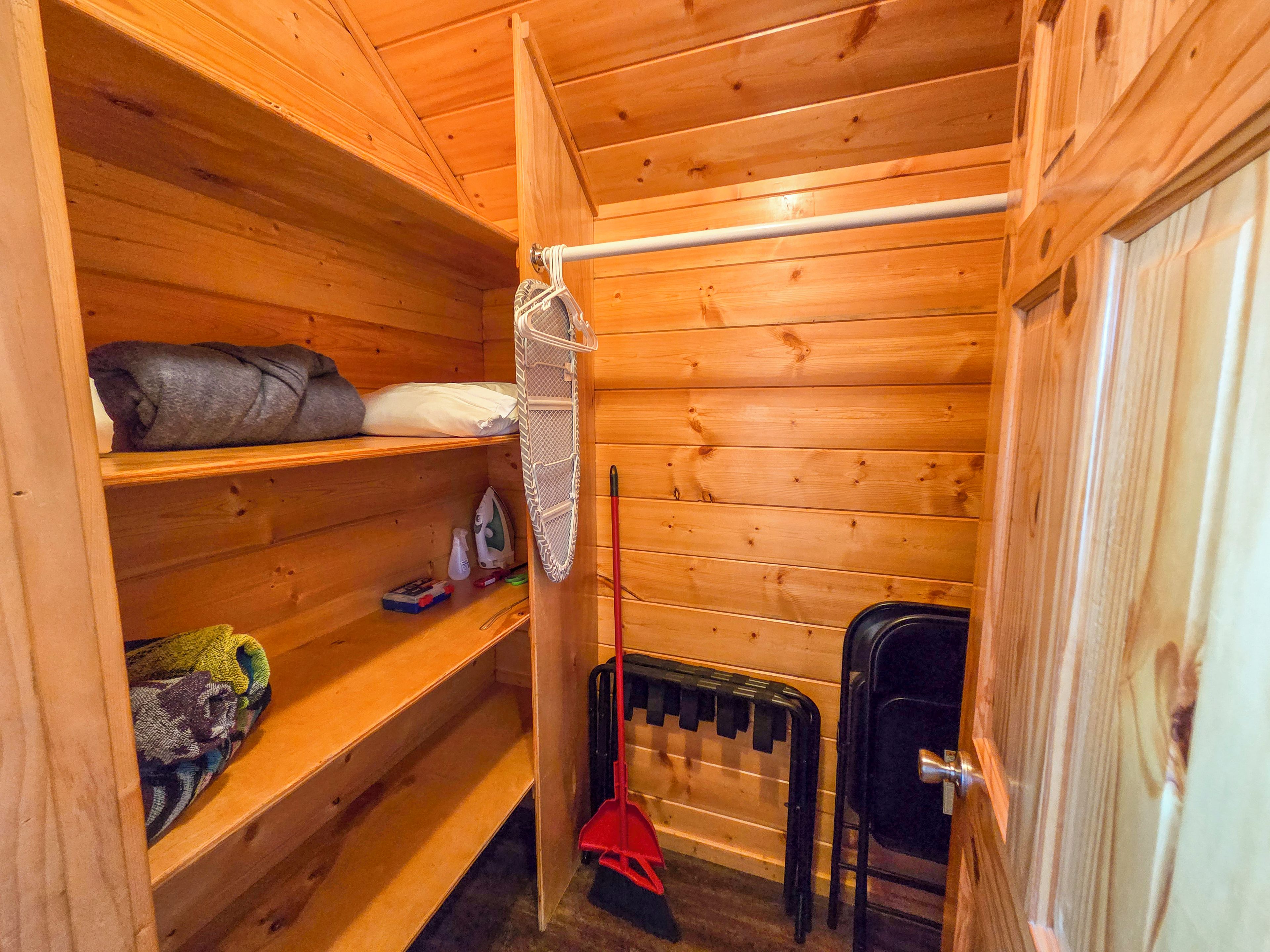A compact wooden room with a bed, shelves, a radiator, and a door.