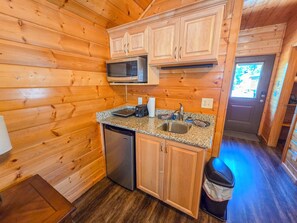 A compact kitchen with wooden cabinetry, a microwave, a sink, and a dishwasher. - Holmstead Ranch Resort (Veyo)