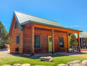 A wooden cabin with a covered porch, a door, and a window.