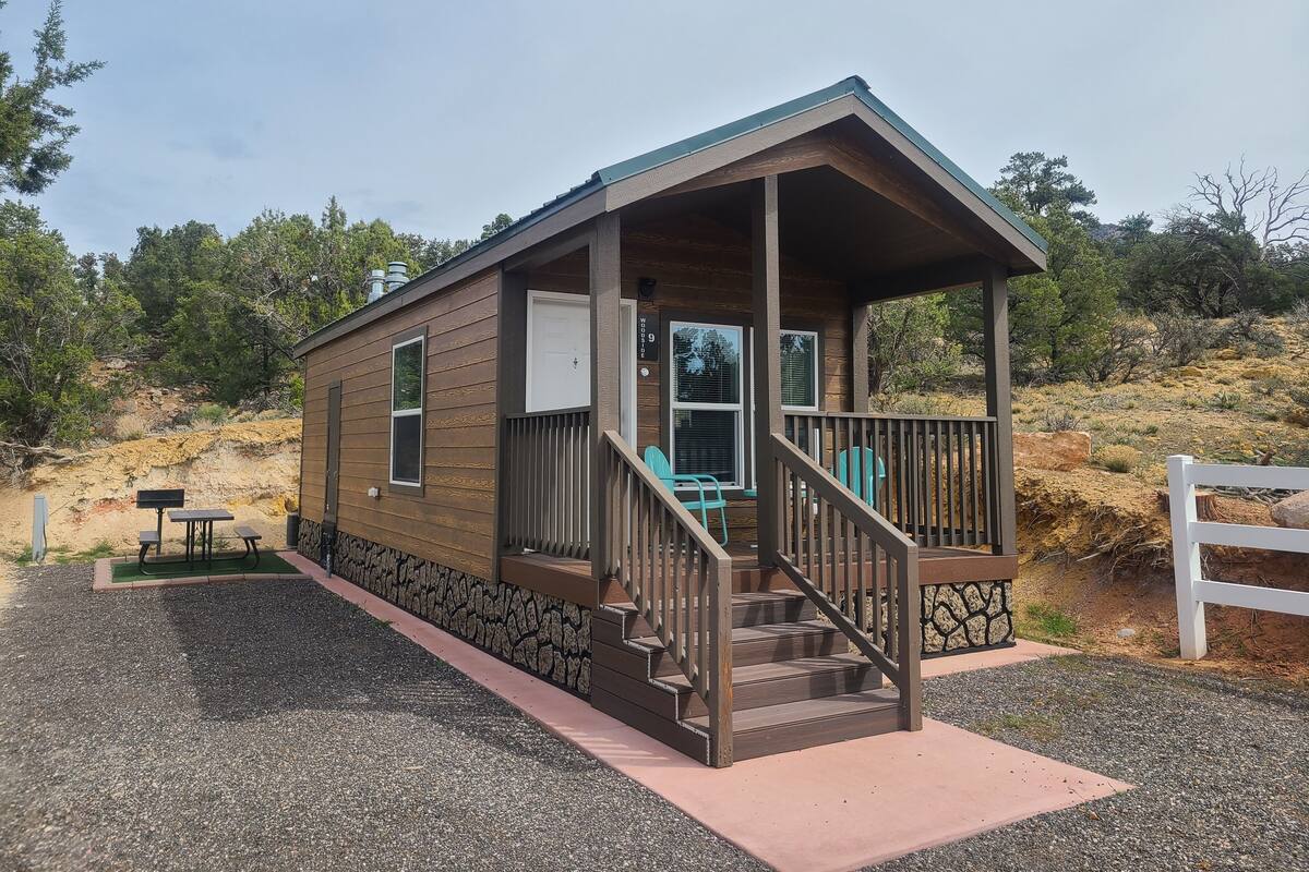 A small cabin with a porch, a staircase, and a mailbox.