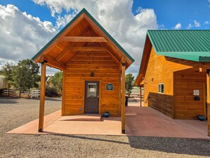 A wooden cabin with a pitched roof, a door, and a sign indicating a guest register. - Holmstead Ranch Resort (Veyo)