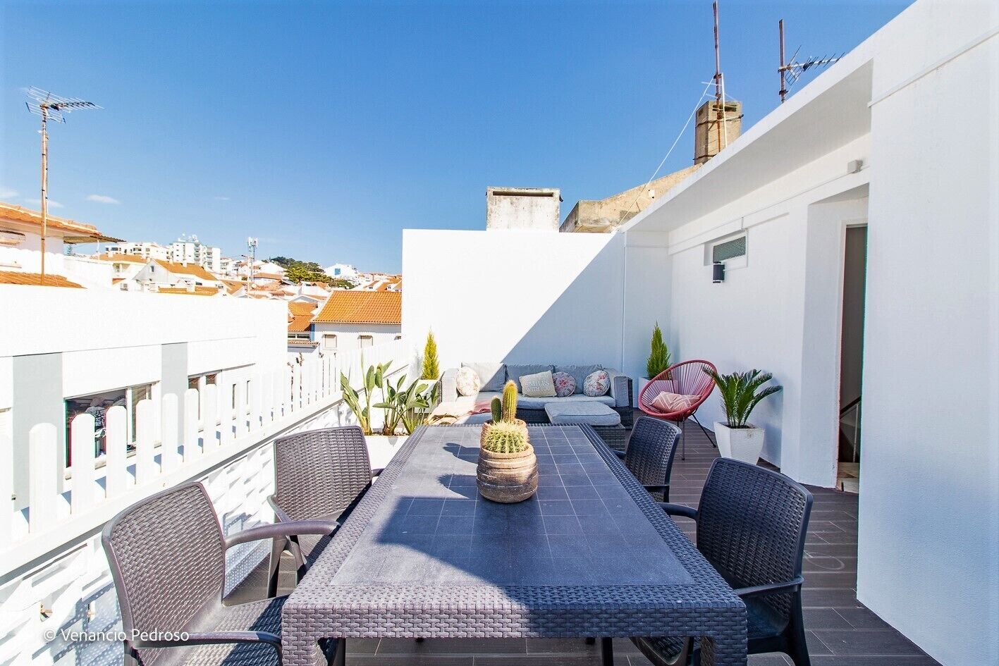 Une terrasse sur le toit, aménagée avec une table à manger, des chaises et des plantes en pot.