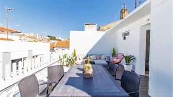 Une terrasse sur le toit, aménagée avec une table à manger, des chaises et des plantes en pot.