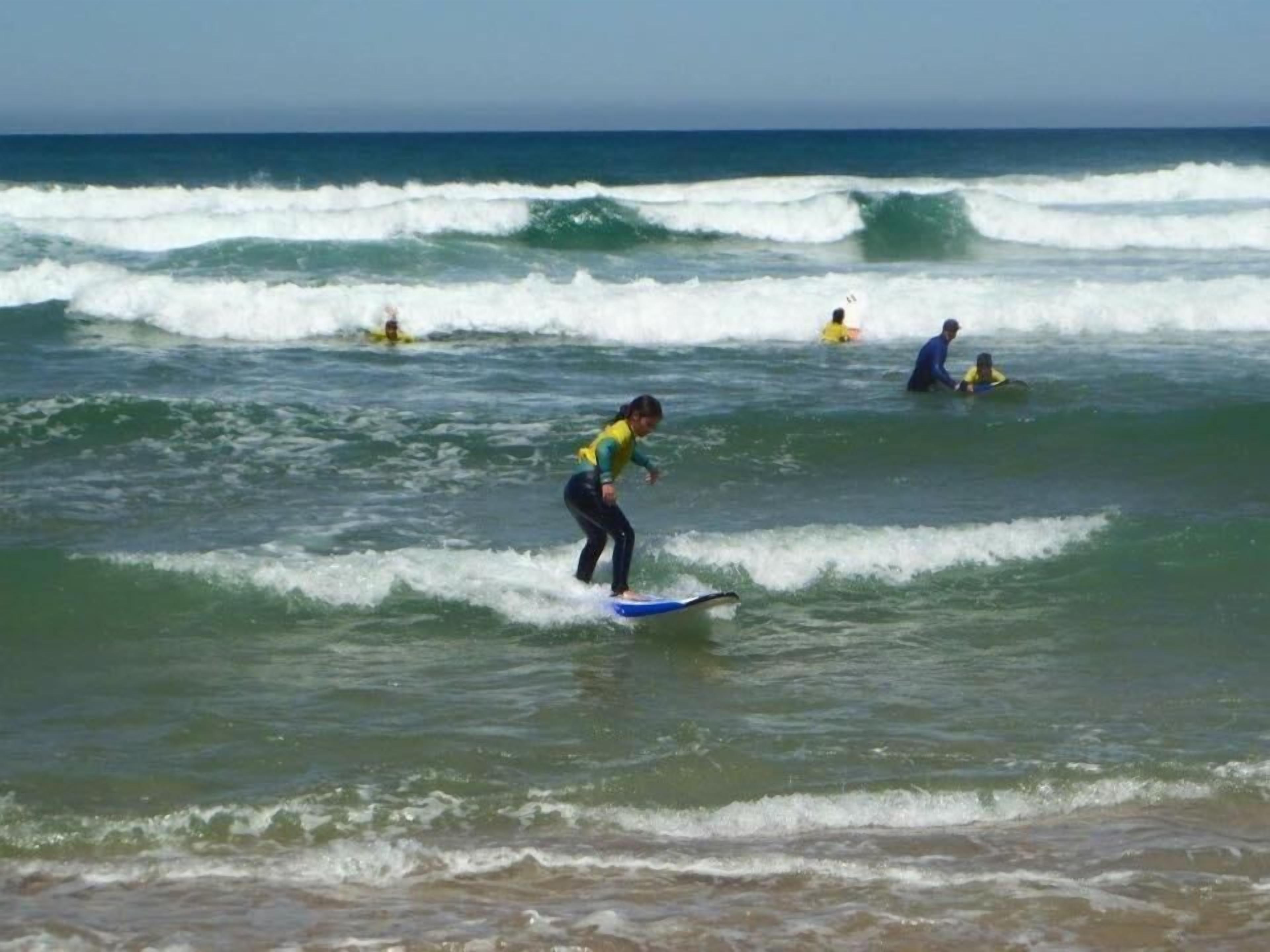 Escena de playa con surfistas y olas.